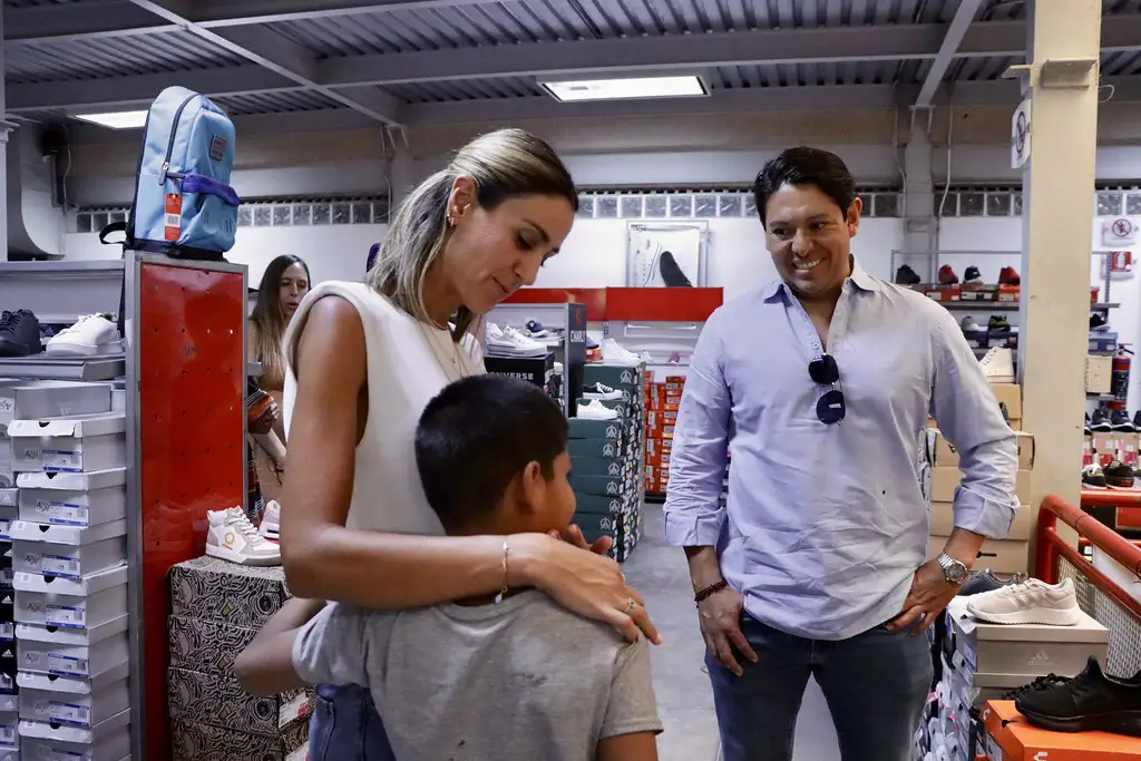 Niño de Barrios Unidos recibe un abrazo de representante de Grupo PLA Firme durante evento de donativo de calzado.