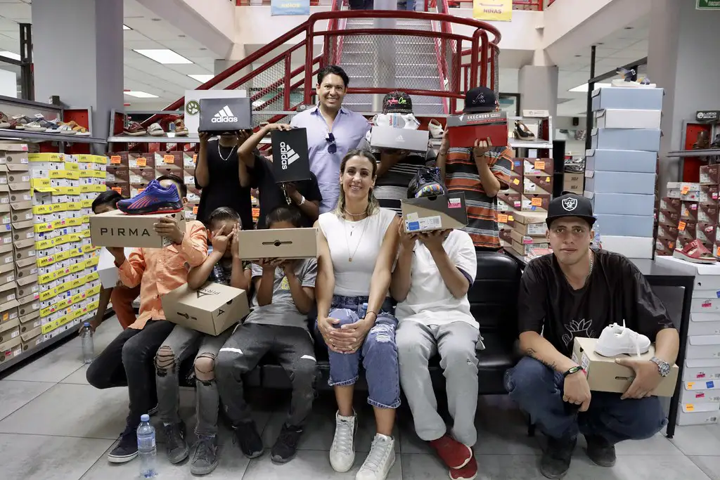 Jóvenes de Barrios Unidos muestran cajas de zapatos tras recibir donativo patrocinado por Grupo PLA Firme y su marca Santa Julia.