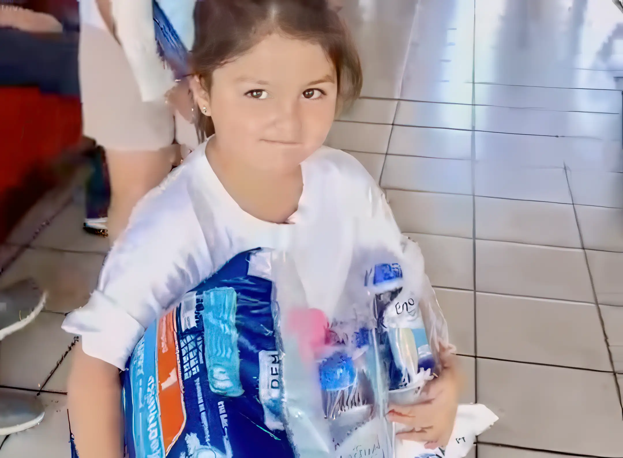 Niña sostiene pañales donados por Grupo PLA Firme durante evento social.