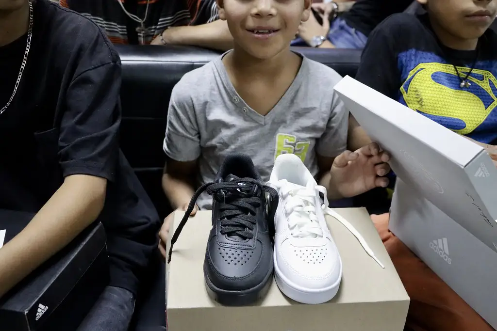 Niño de Barrios Unidos sostiene un par de tenis donados gracias a Grupo PLA Firme y Santa Julia.