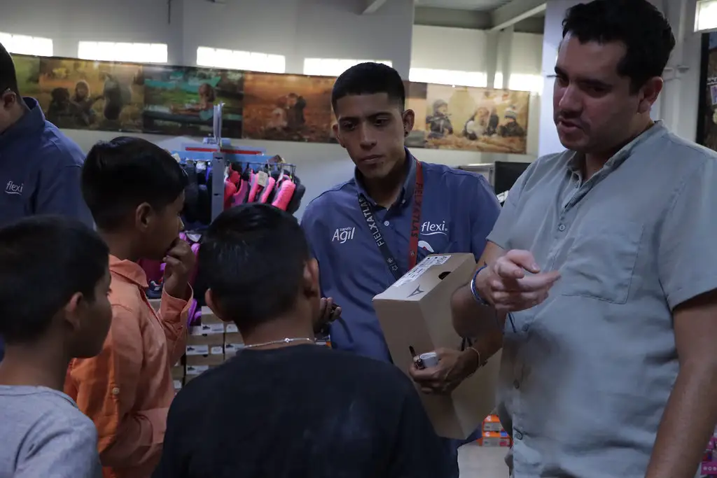 Representantes de Grupo PLA Firme brindan orientación a jóvenes durante entrega de zapatos en Barrios Unidos, con apoyo de Santa Julia.